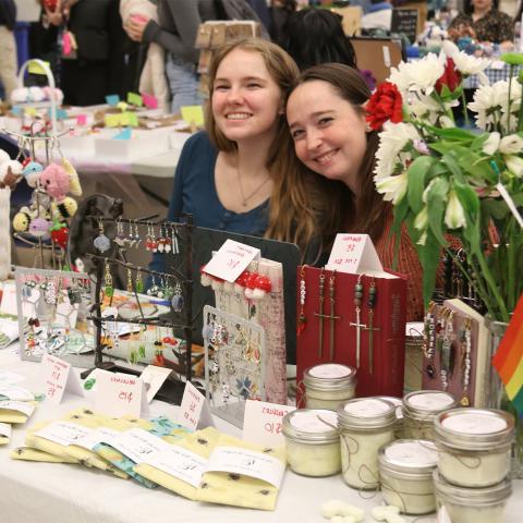 Two students posing at table with candles and jewlery.